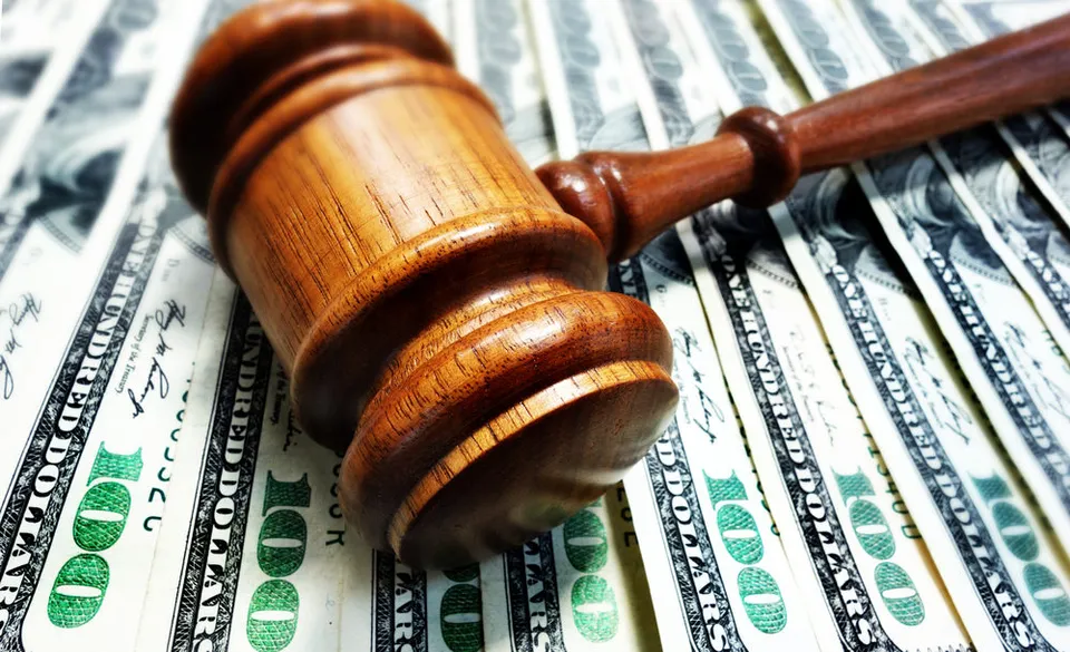 A judge's gavel rests atop a spread of 100 dollar bills