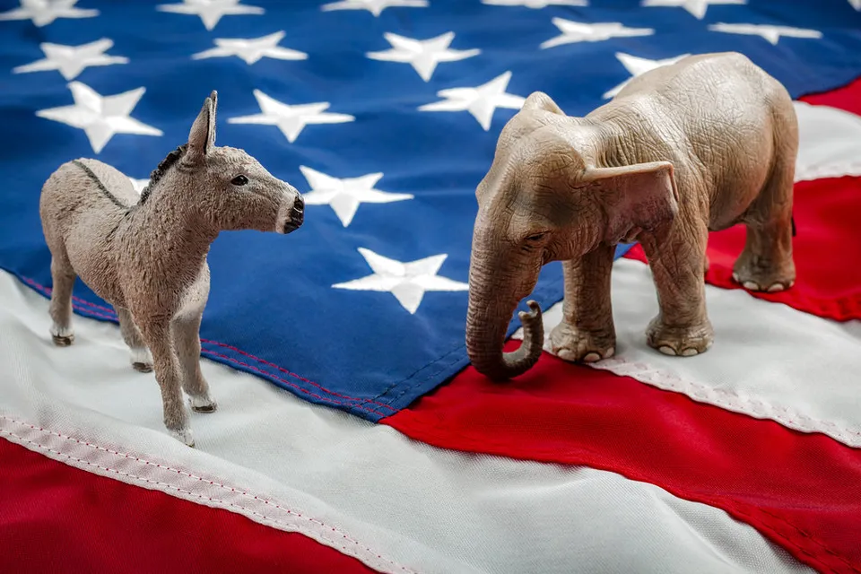 The symbols of the Republican and Democratic parties (elephant and donkey) stand atop a US flag