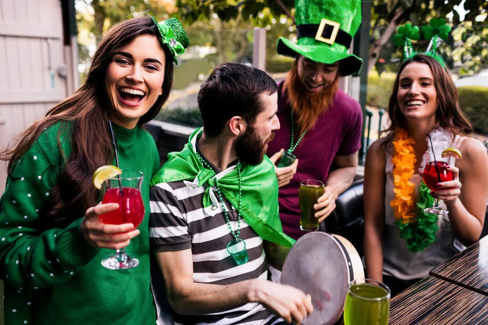 A group of young partiers dressed in green enjoying cocktails and green beer